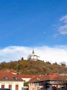 there is a clock tower on the top of this hill in town center, with buildings below it