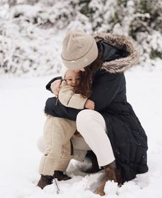 a woman holding a child in the snow