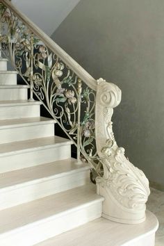 a white staircase with wrought iron handrails and flowers on the baluster