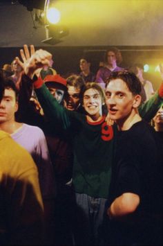 a group of young men standing next to each other in front of a crowd holding up their hands