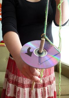 a woman is holding a cd with a string attached to it and pulling the disc