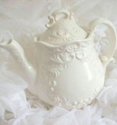 a white tea pot sitting on top of a bed