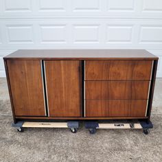 a wooden cabinet sitting on wheels in front of a garage door