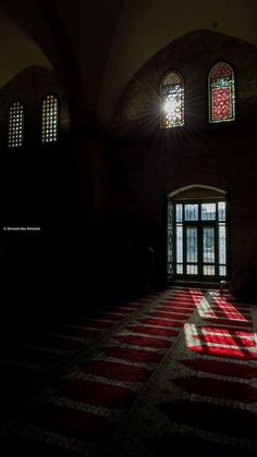 the sun shines through two stained glass windows in an old building with red and white stripes on the floor