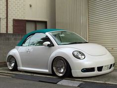 a small white car parked on the side of a street next to a garage door