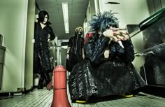 two people dressed in black and one with blue hair are walking down an elevator way