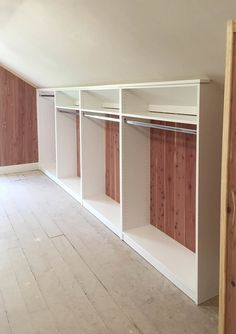 an empty room with wooden closets and white shelving units on the wall,