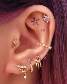 a woman with purple hair wearing three different ear piercings and one has pink hair