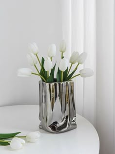 white tulips in a silver vase on a table