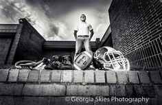 a black and white photo of a man standing next to football equipment on the side of a building