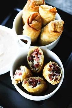 small bowls filled with food sitting on top of a black tray next to a bowl of dip