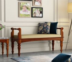 a wooden bench sitting on top of a floor next to a wall with pictures above it