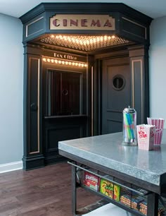 the entrance to a movie theater with popcorn, soda and drinks on the table in front of it