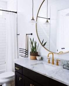 a bathroom with marble counter tops and gold fixtures, along with a round mirror above the sink