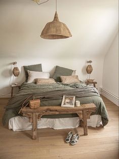 a bed sitting in a bedroom next to a wooden table with shoes on top of it