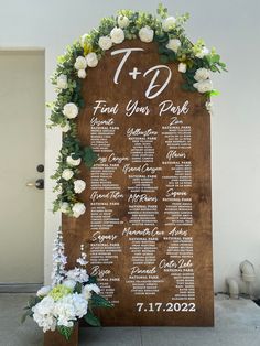 a wooden sign with flowers and greenery on it