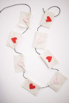 paper hearts are attached to twine strings on a white surface with black and red string