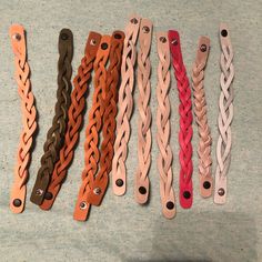 five different colored leather bracelets are lined up on a counter top next to each other