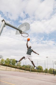 a man jumping up to dunk a basketball into the hoop on an outdoor court