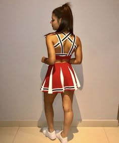 a woman standing in front of a wall wearing a red and white dress with stripes