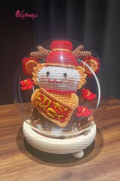 a crocheted teddy bear under a glass dome