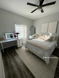 a bedroom with a bed, desk and ceiling fan in the middle of the room