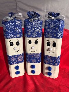 two blue and white painted wooden blocks with faces on them sitting on a red cloth