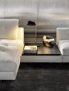 a modern living room with white couches and a coffee table in front of it