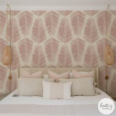 a bed with pillows and decorative wallpaper in a room that has pink feathers on it