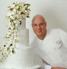 a man standing next to a tall white cake