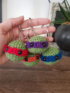 a hand holding three crocheted keychains in the shape of turtles