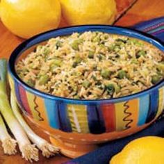 a bowl filled with rice next to lemons and celery on a table