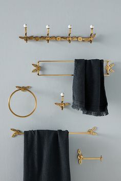 three towel hooks and two towels hanging on the wall next to each other with gold hardware