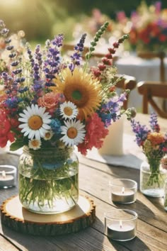 a table topped with vases filled with lots of different colored flowers and greenery