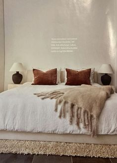 a white bed with pillows and blankets on it