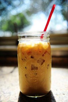 a mason jar filled with liquid sitting on top of a table next to a window