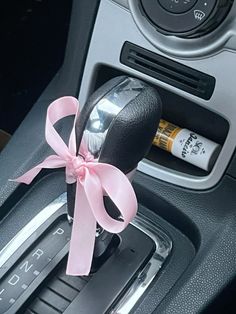 a steering wheel with a pink ribbon and an empty bottle in the center cup holder