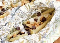 two hotdogs covered in chocolate chips and melted marshmallows on tin foil