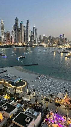 an aerial view of a city and the ocean with boats in the water at night