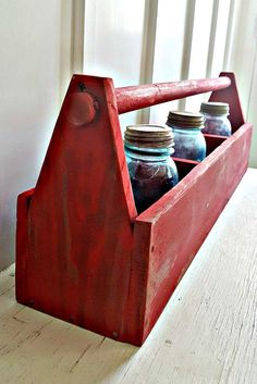 an old wooden box with jars in it sitting on a table next to a window