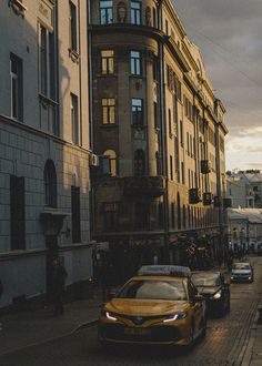 cars are parked on the street in front of tall buildings