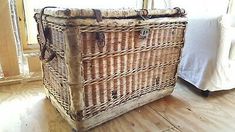 a large wicker basket sitting on top of a wooden floor next to a bed