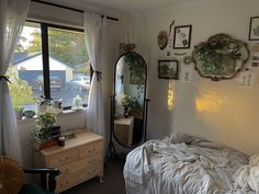 a bedroom with a bed, dresser and mirror in front of a large window overlooking the street