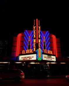 the marquee is lit up at night with cars parked in front of it