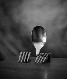 a spoon sitting on top of a wooden table next to two forks and a knife