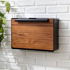 a wooden plaque mounted to the side of a white brick wall next to a potted plant