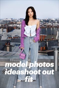 a woman standing on top of a roof next to a pink purse and purple jacket