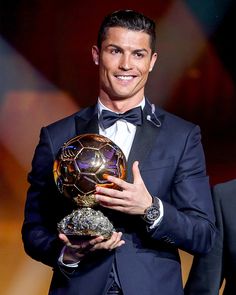 a man in a tuxedo holding a ballon d'or award on stage