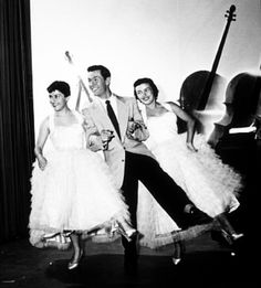 three people in tulle skirts are posing for a photo while one man is leaning on the piano