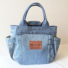 a blue jean bag with leather label on the front and side pockets, sitting on a white surface